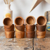 Papoose Toys 12 small natural wooden bowls placed on a wooden desk. 