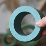 Large Papoose Toys nesting tube in earth blue in an adult's hand.