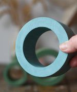 Large Papoose Toys nesting tube in earth blue in an adult's hand.