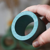 Medium Papoose Toys nesting tube in earth blue in an adult's hand.