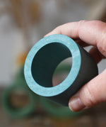 Medium Papoose Toys nesting tube in earth blue in an adult's hand.