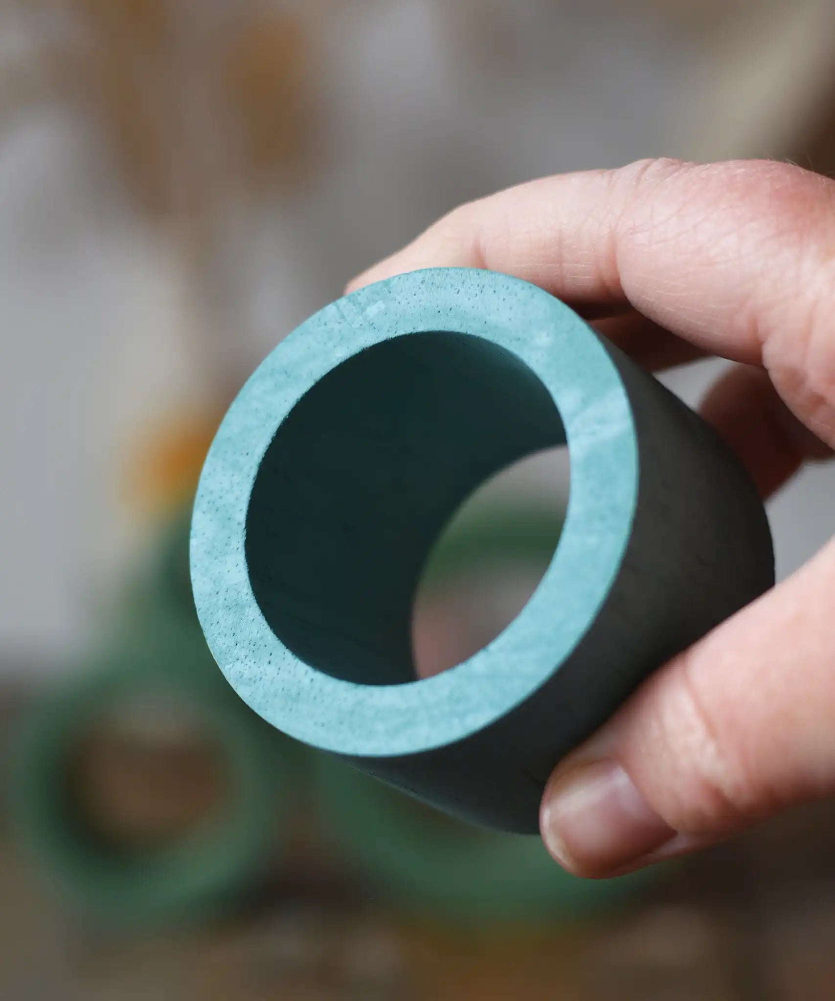 Medium Papoose Toys nesting tube in earth blue in an adult's hand.