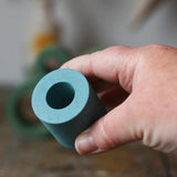 Small Papoose Toys nesting tube in earth blue in an adult's hand.