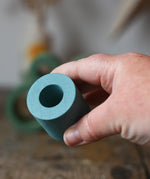 Small Papoose Toys nesting tube in earth blue in an adult's hand.