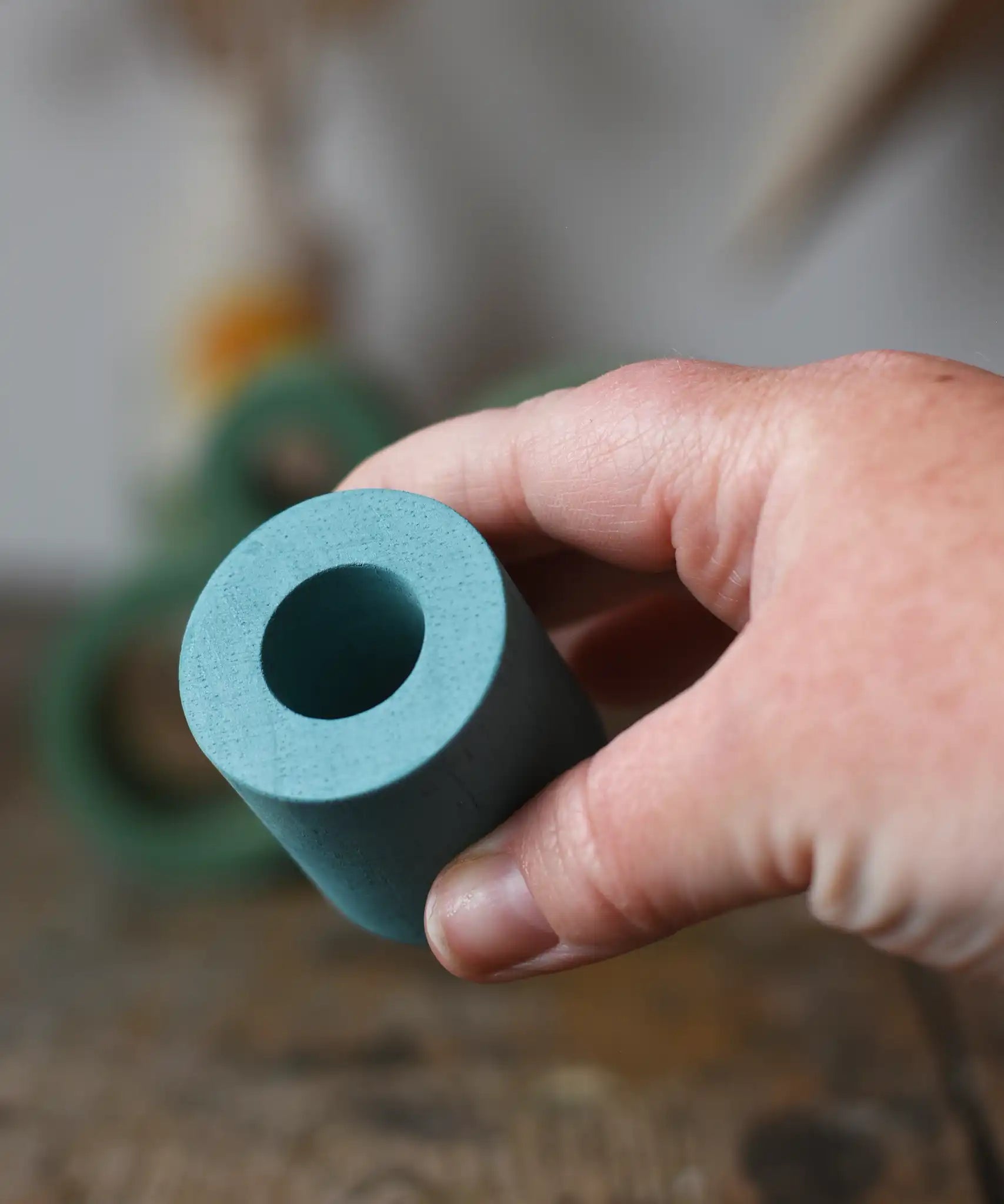 Small Papoose Toys nesting tube in earth blue in an adult's hand.
