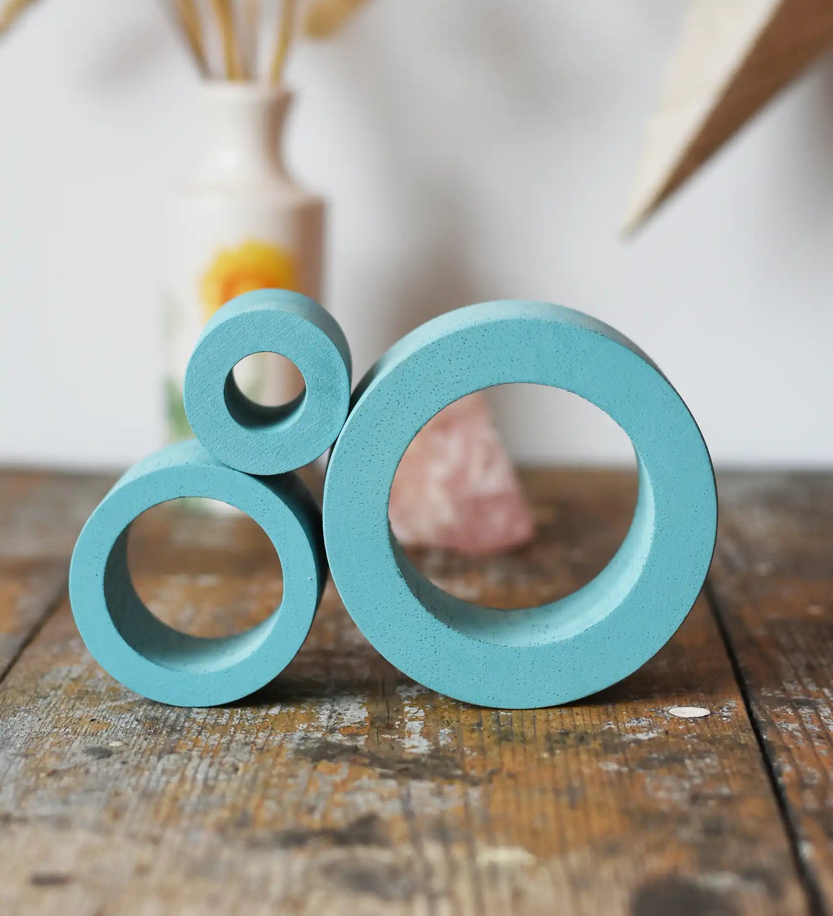 Papoose Toys nesting tubes in earth blue stacked on a wooden desk. 