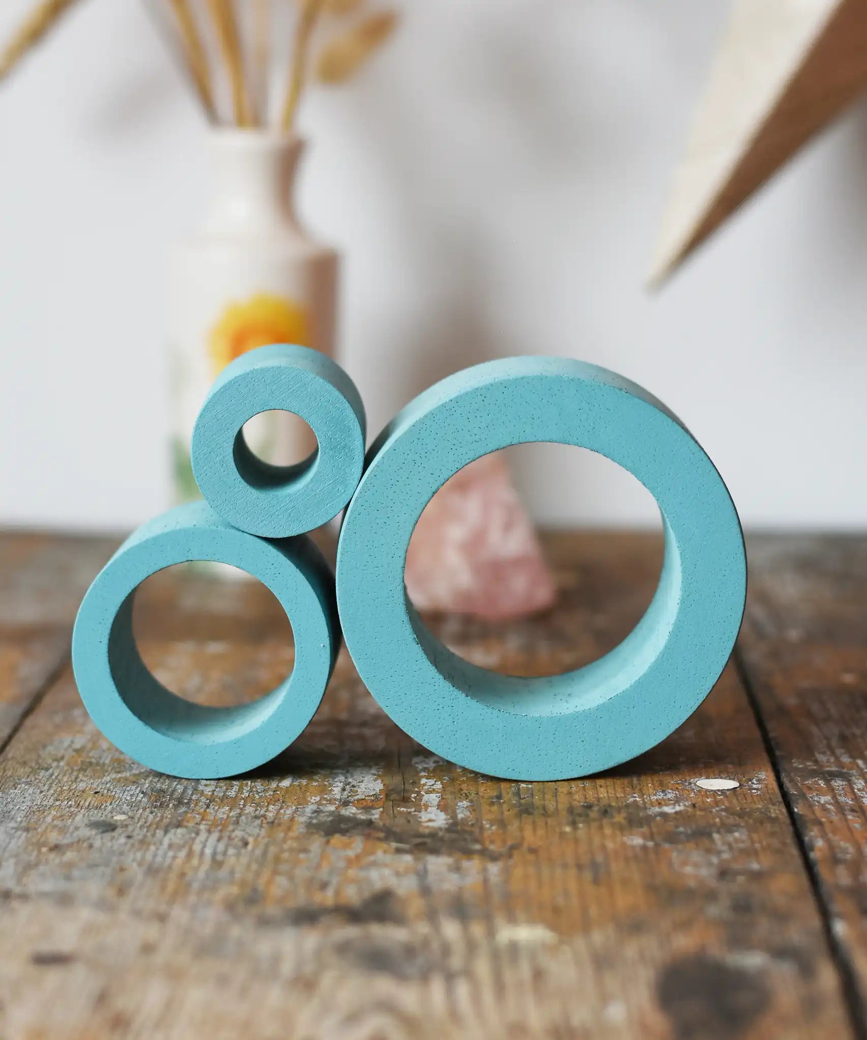 Papoose Toys nesting tubes in earth blue stacked on a wooden desk. 