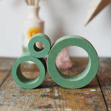Papoose Toys nesting tubes in earth green stacked on a wooden desk. 