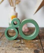 Papoose Toys nesting tubes in earth green stacked on a wooden desk. 