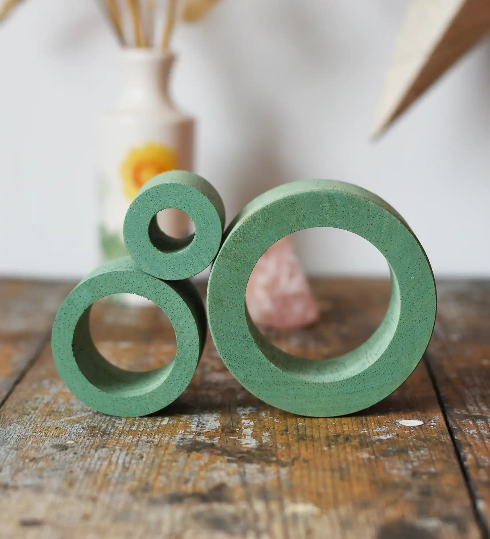 Papoose Toys nesting tubes in earth green stacked on a wooden desk. 