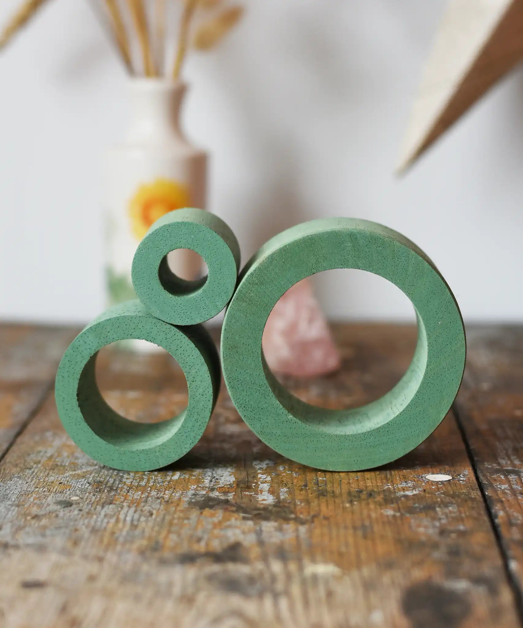 Papoose Toys nesting tubes in earth green stacked on a wooden desk. 
