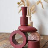 Papoose Toys nesting tubes in earth red stacked on a wooden desk into the shape of a train. 