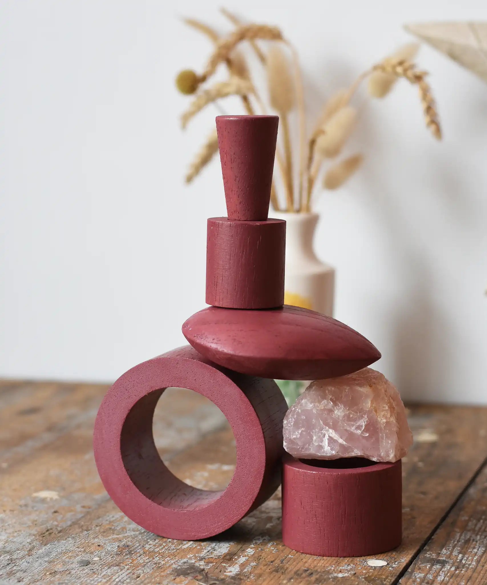 Papoose Toys nesting tubes in earth red stacked on a wooden desk into the shape of a train. 