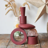 Papoose Toys nesting tubes in earth red stacked on a wooden desk into the shape of a train. 