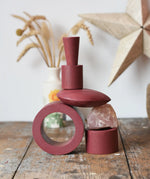 Papoose Toys nesting tubes in earth red stacked on a wooden desk into the shape of a train. 
