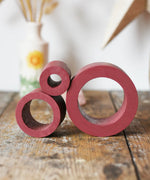 Papoose Toys nesting tubes in earth red on a wooden desk. 