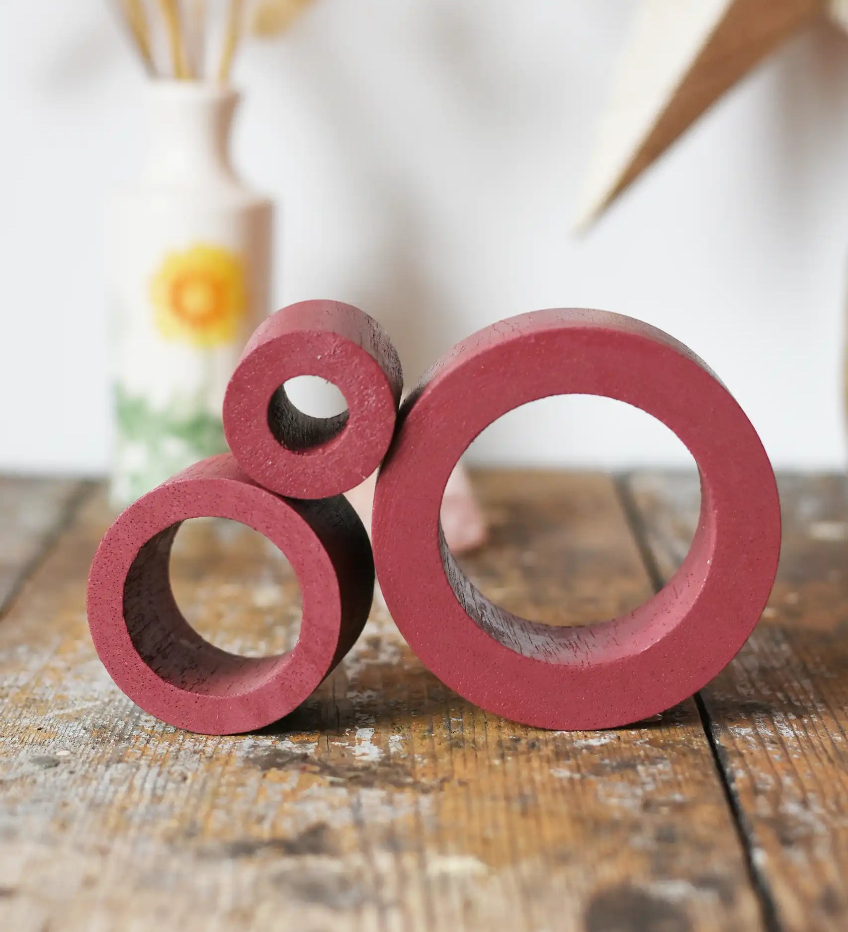Papoose Toys nesting tubes in earth red on a wooden desk. 