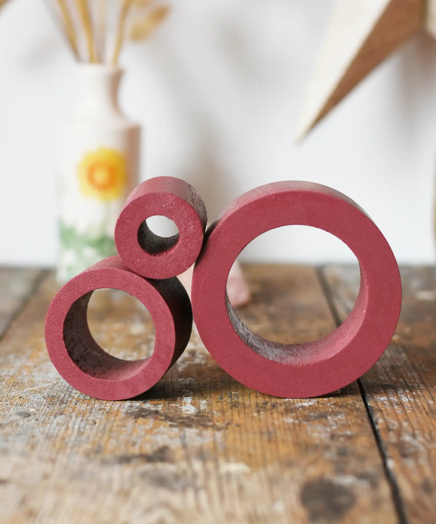 Papoose Toys nesting tubes in earth red on a wooden desk. 