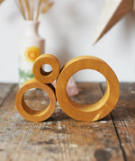 Papoose Toys nesting tubes in earth yellow on a wooden desk. 