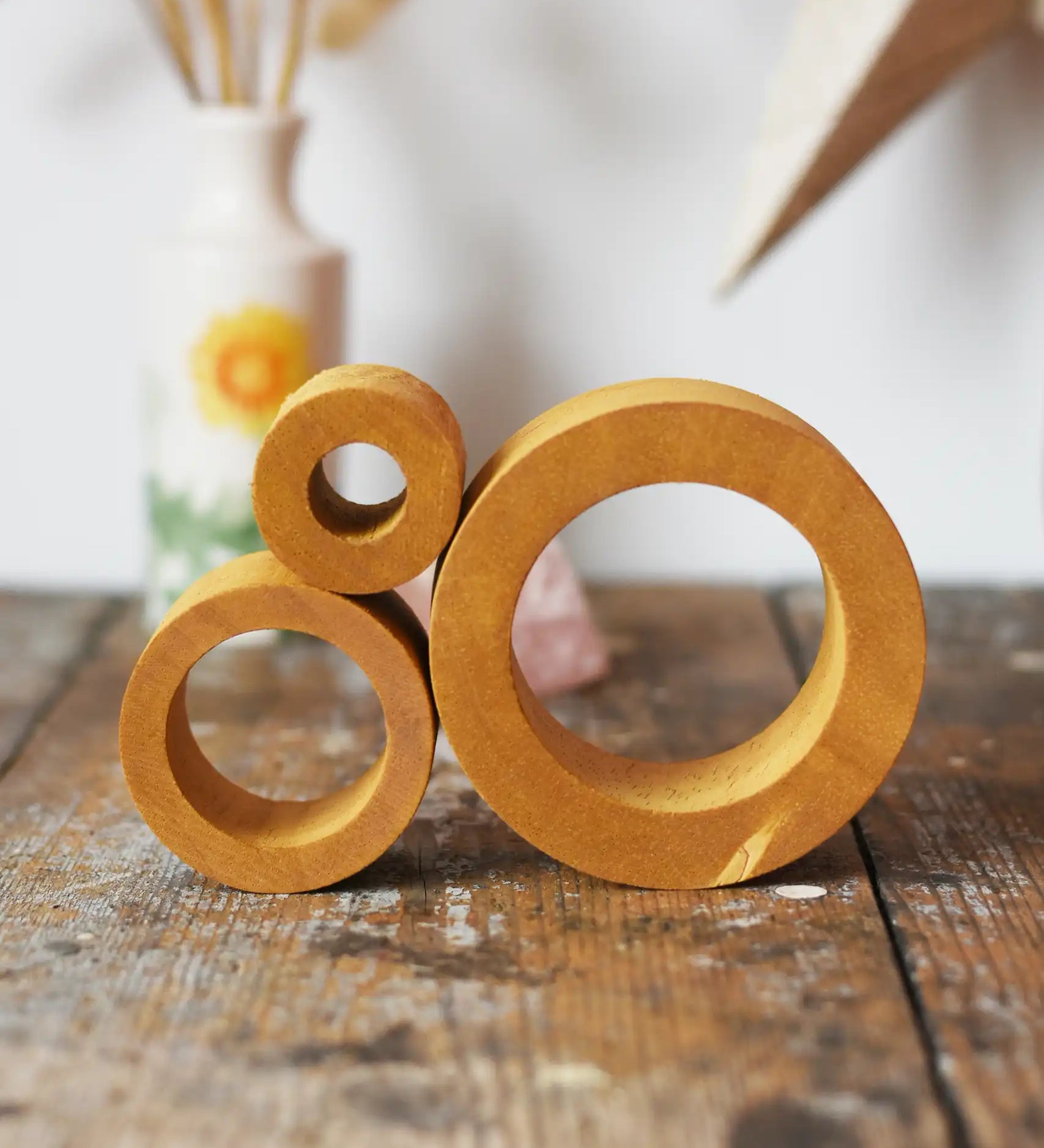 Papoose Toys nesting tubes in earth yellow on a wooden desk. 