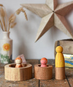 Papoose Toys nesting tubes natural wooden rings placed on a wooden desk with wild crew peg dolls placed on and in them. 
