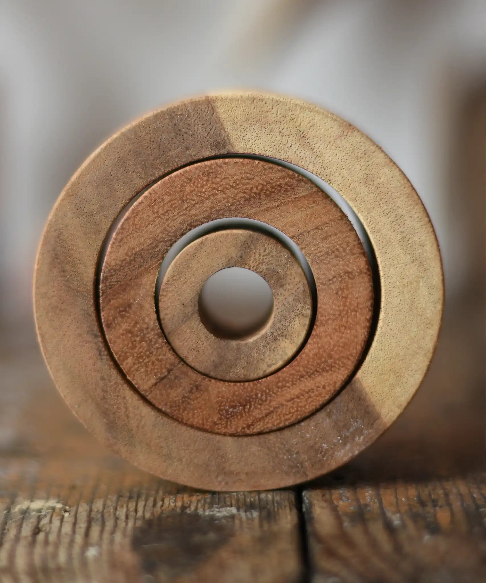 Papoose Toys nesting tubes natural wooden rings placed on a wooden desk. 