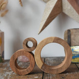 Papoose Toys nesting tubes natural wooden rings stacked on a wooden desk. 