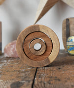 Papoose Toys nesting tubes natural wooden rings placed on a wooden desk. 