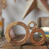 Papoose Toys nesting tubes natural wooden rings stacked on a wooden desk. 