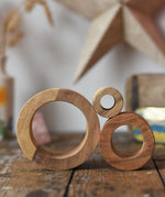 Papoose Toys nesting tubes natural wooden rings stacked on a wooden desk. 