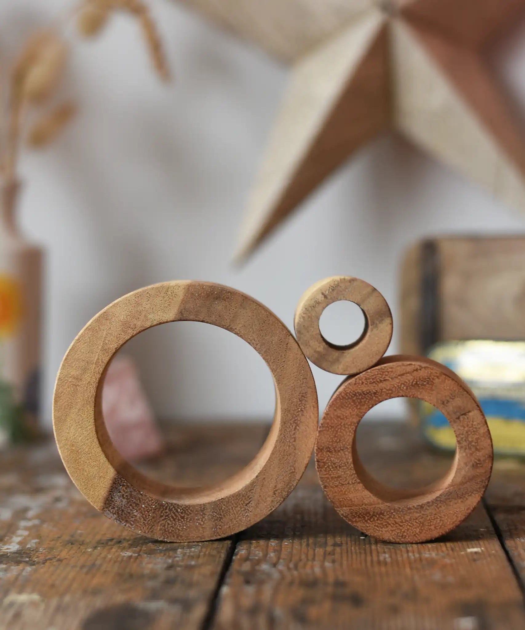 Papoose Toys nesting tubes natural wooden rings stacked on a wooden desk. 