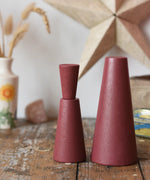 Papoose Toys wooden stacking cones in earth red placed on a wooden desk.