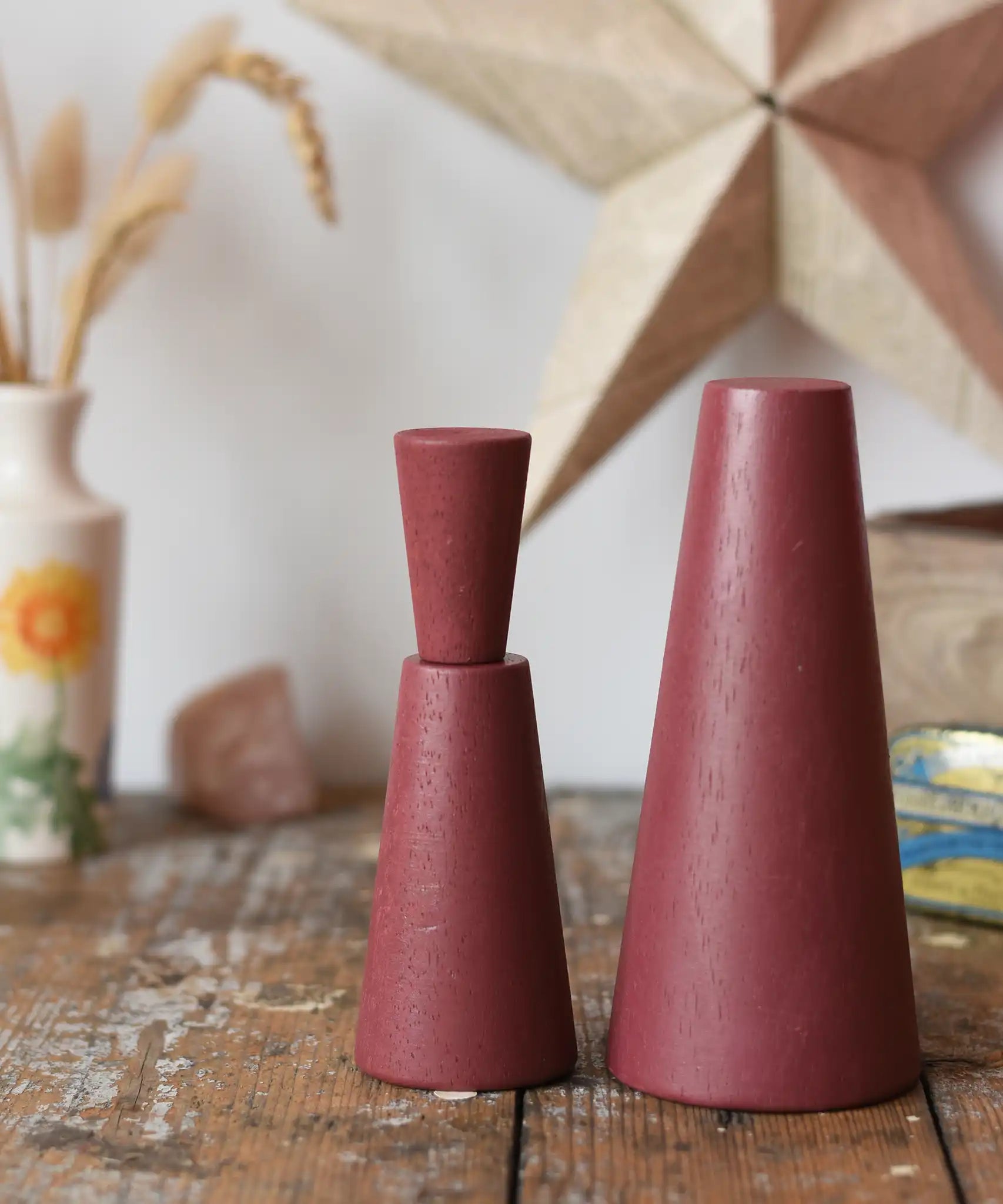 Papoose Toys wooden stacking cones in earth red placed on a wooden desk.