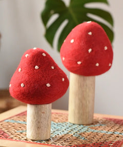 Papoose Toys felt toadstool wooden toy set placed on a rattan top stool. 
