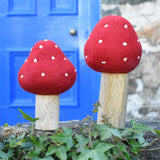 Papoose Toys felt toadstool wooden toy set placed on stone wall outdoors.