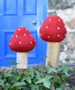 Papoose Toys felt toadstool wooden toy set placed on stone wall outdoors.