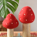 Papoose Toys felt toadstool wooden toy set placed on a rattan top stool. 