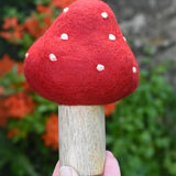 Small Papoose Toys felt toadstool wooden toy in an adult's hand.