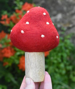 Small Papoose Toys felt toadstool wooden toy in an adult's hand.