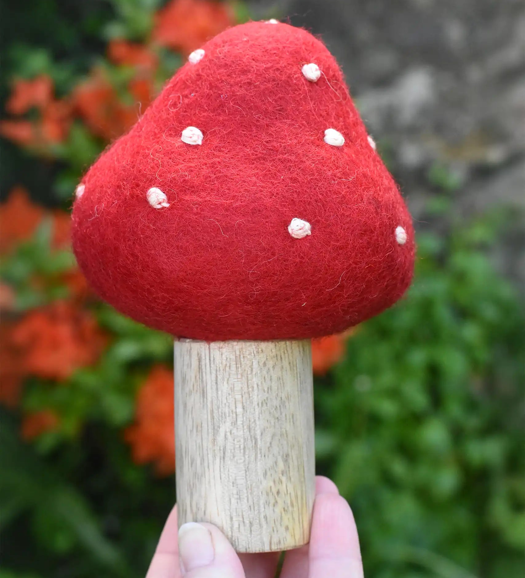 Small Papoose Toys felt toadstool wooden toy in an adult's hand.