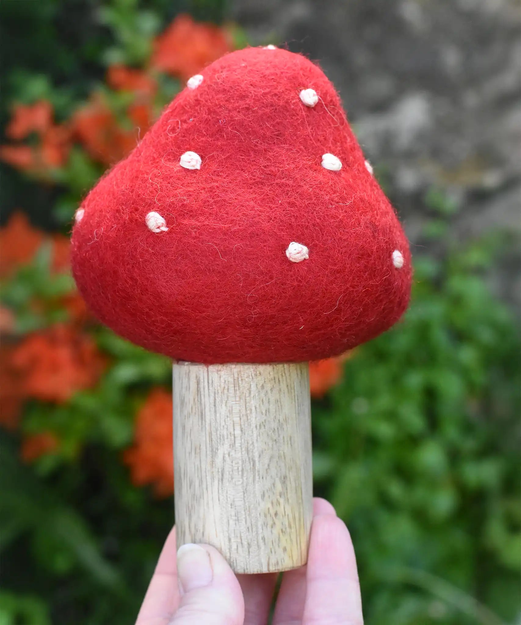 Small Papoose Toys felt toadstool wooden toy in an adult's hand.