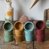 Papoose Toys wooden bowls in earth colours stacked up on a wooden desk.