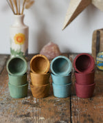 Papoose Toys wooden bowls in earth colours stacked up on a wooden desk.