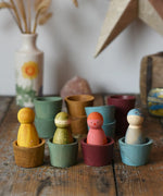 Papoose Toys wooden bowls in earth colours with Grapat Wild Crew peg dolls placed inside.