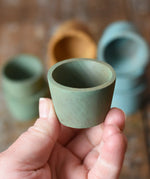 Green Papoose Toys wooden bowl in an adult's hand.