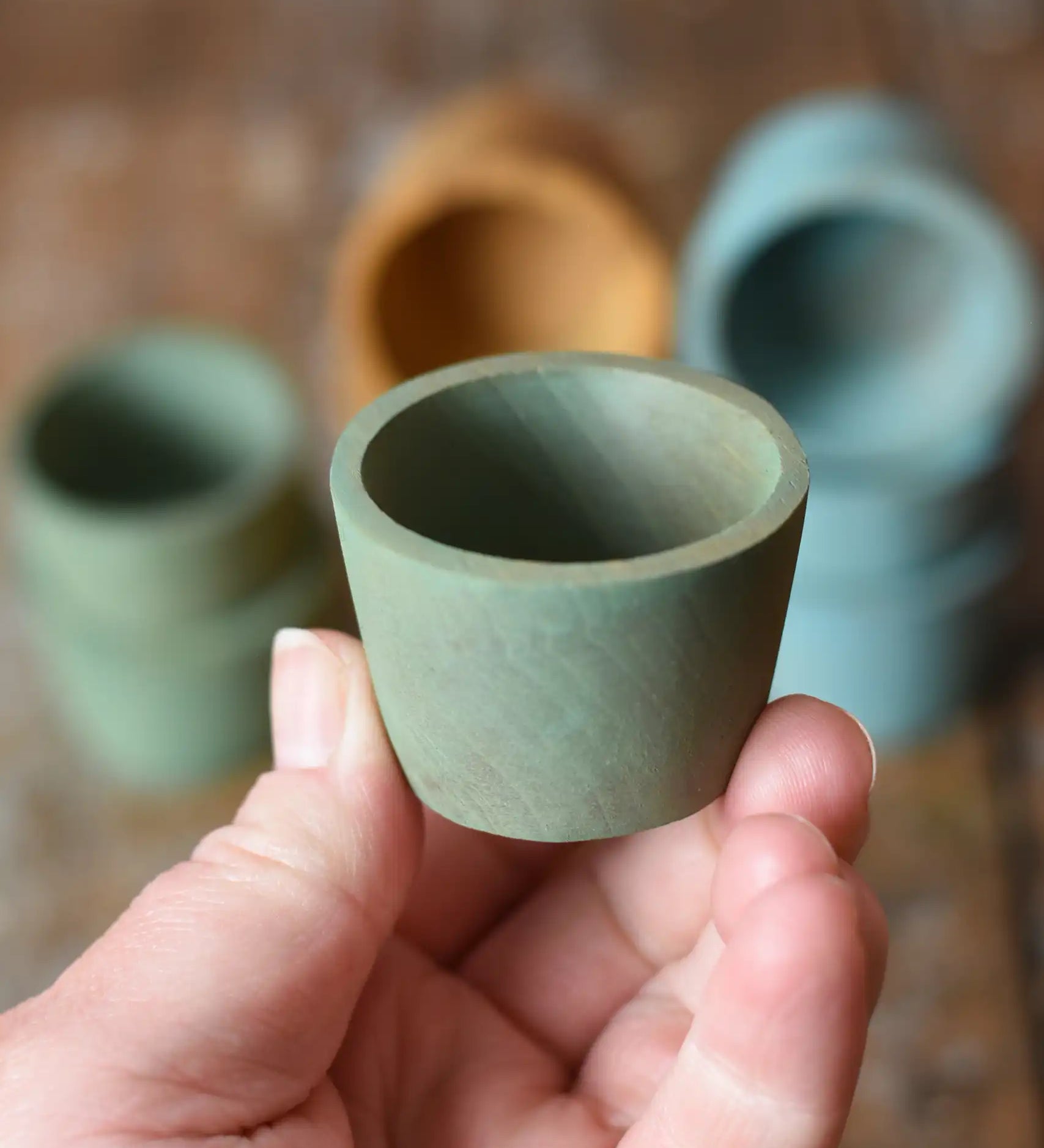 Green Papoose Toys wooden bowl in an adult's hand.