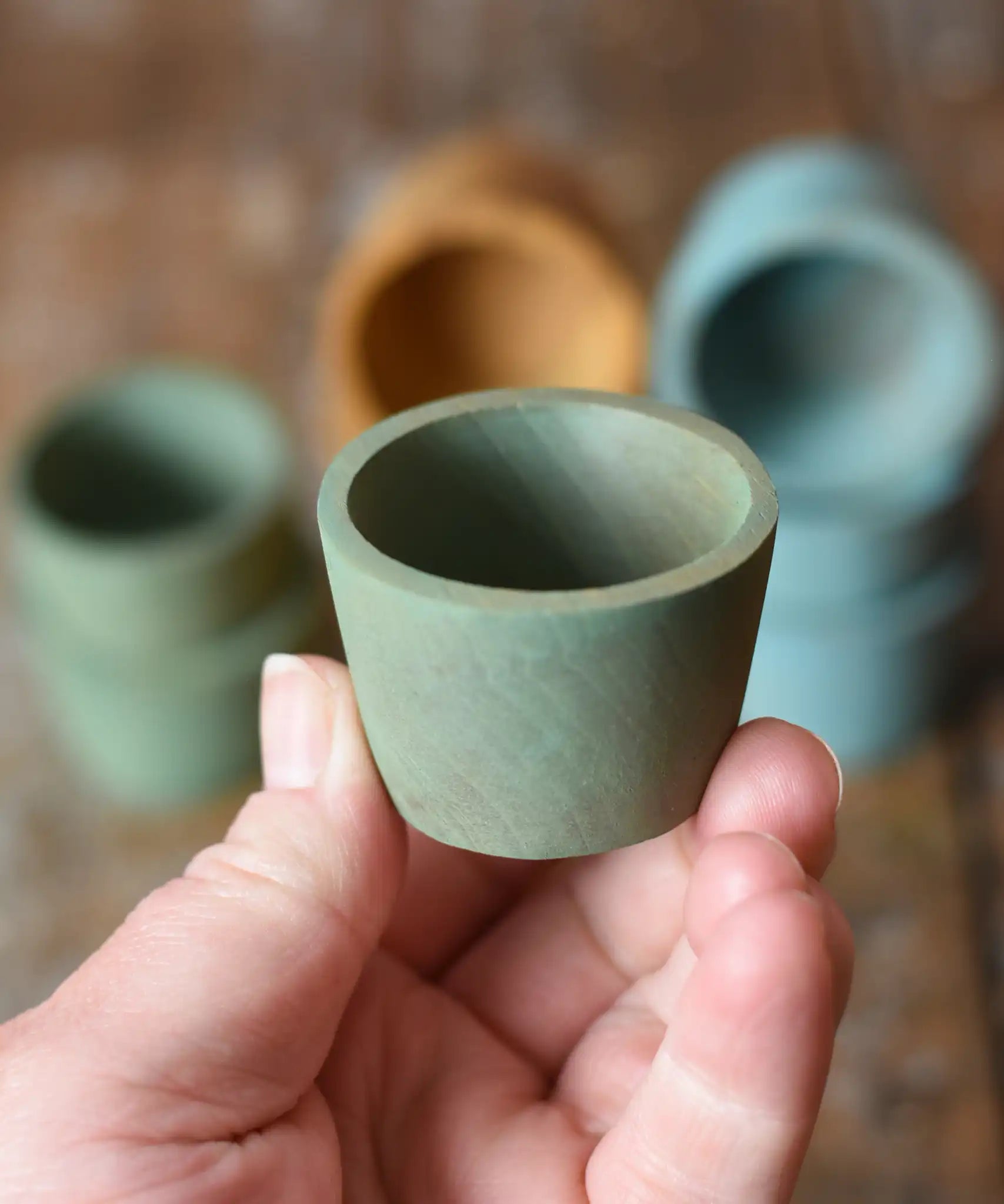 Green Papoose Toys wooden bowl in an adult's hand.