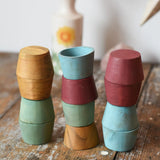 Papoose Toys wooden bowls in earth colours stacked up on a wooden desk.