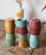 Papoose Toys wooden bowls in earth colours stacked up on a wooden desk.
