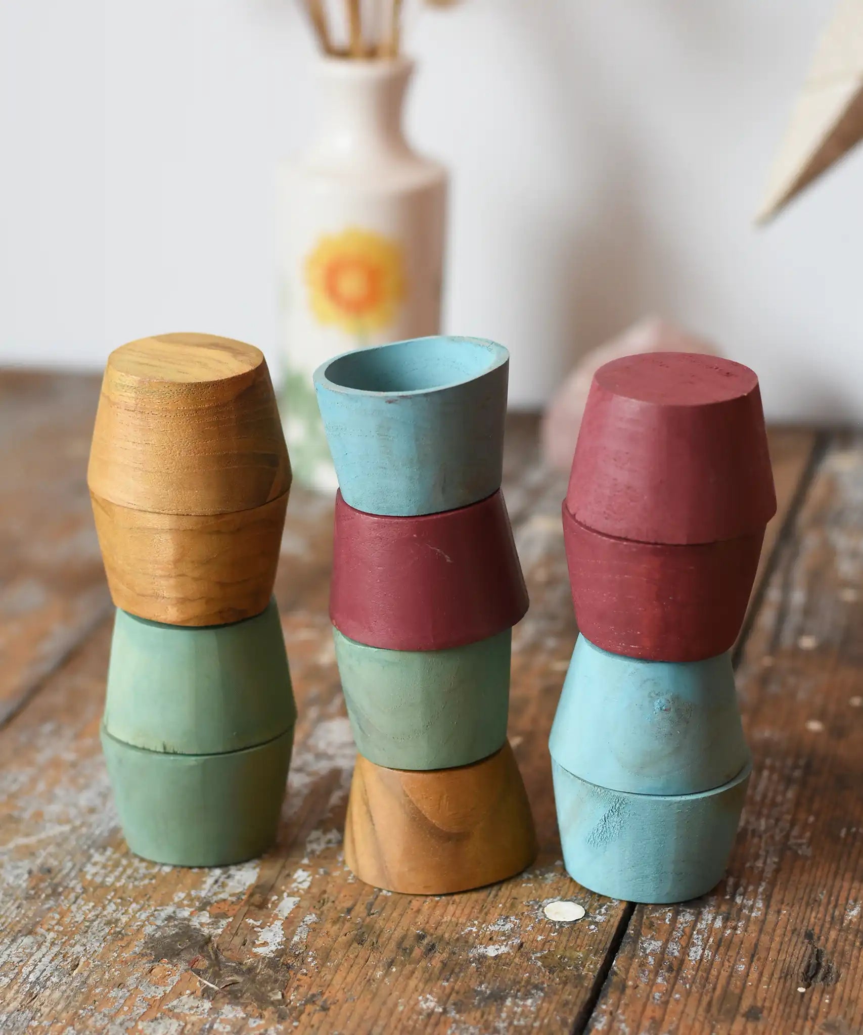 Papoose Toys wooden bowls in earth colours stacked up on a wooden desk.